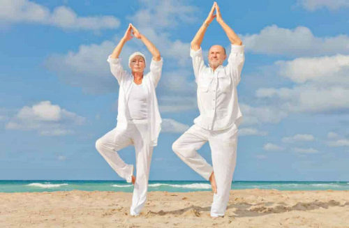 an old couple doing yoga on the beach 1024x670